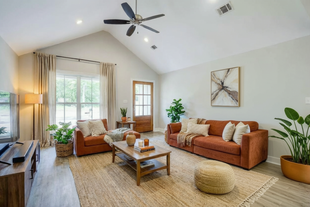open concept living room with vaulted ceiling, ceiling fan, neutral decor, and cozy seating in modern farmhouse house plan